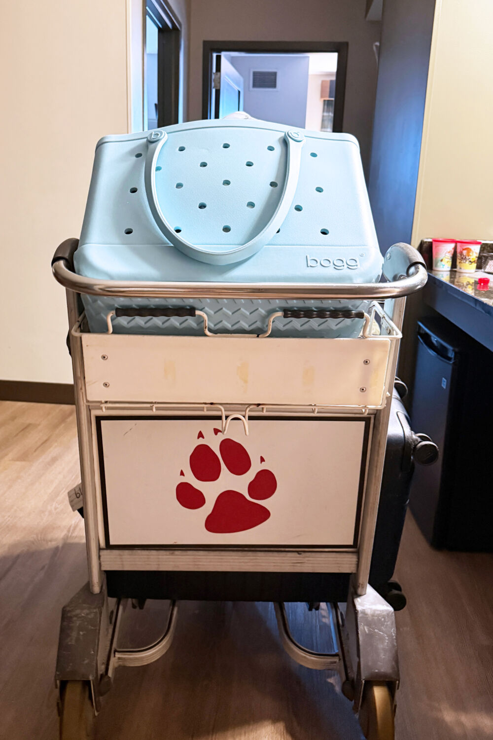 A blue Bogg bag and luggage on a resort cart featuring a wolf paw print logo.