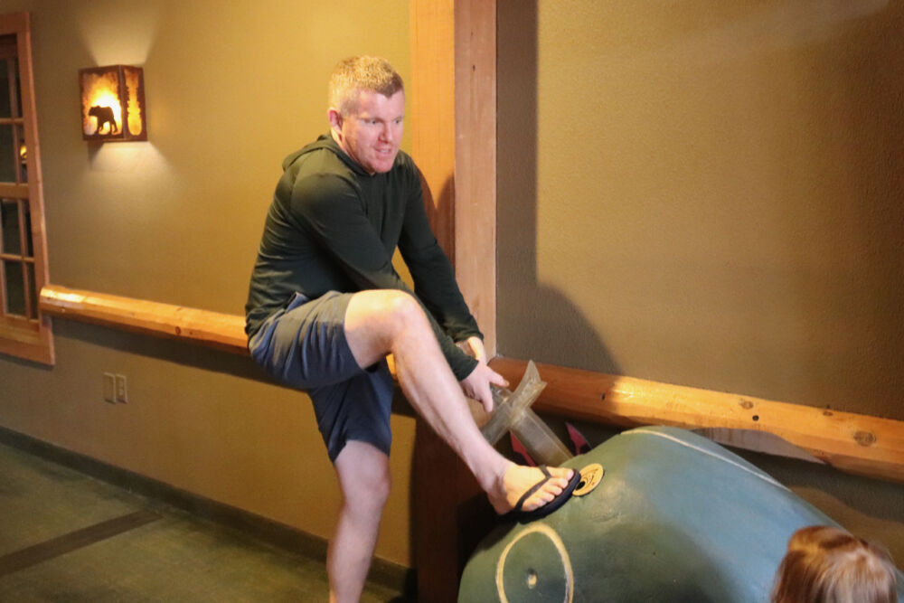 A father playing with his children on a wooden log feature inside the resort.