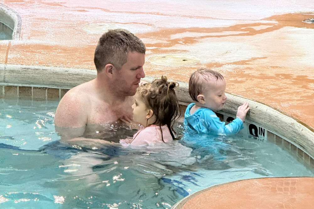 A father and his two children splashing in the dedicated kid-friendly hot tub.