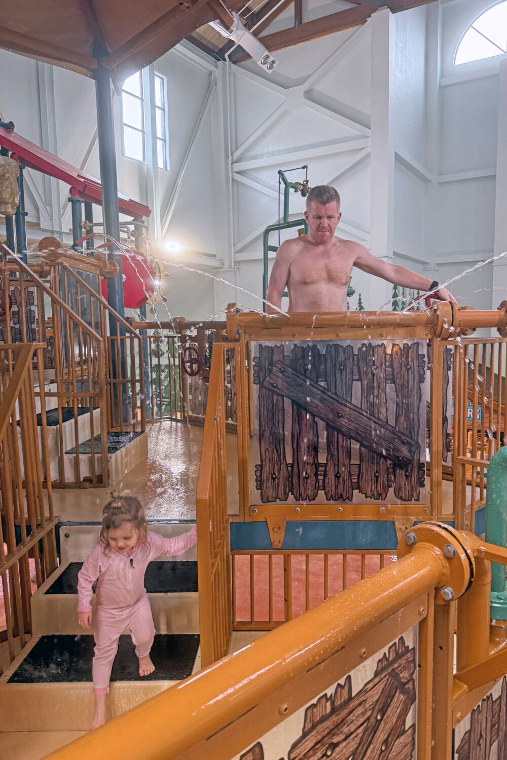 A young girl walking down steps of a wooden water tower play structure.