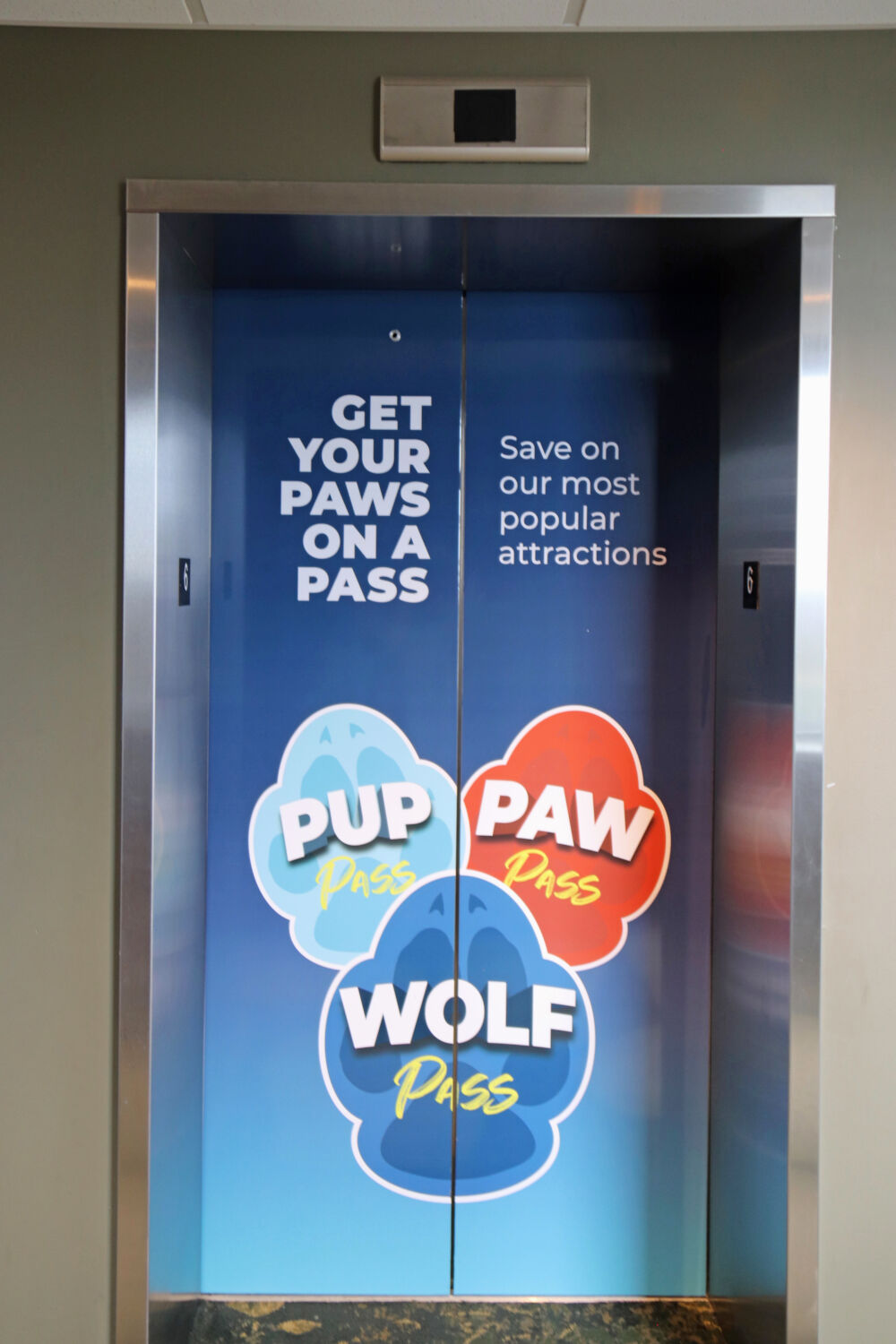 Elevator doors showing an advertisement for Pup, Paw, and Wolf passes.